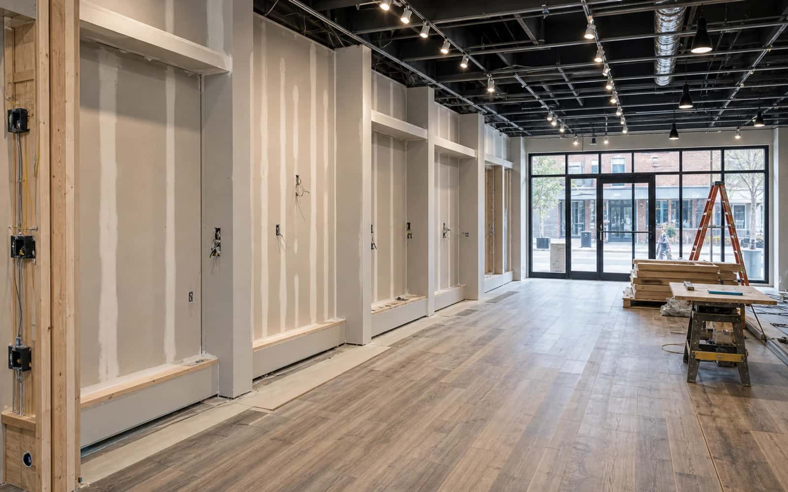 Retail fitout in progress with walls, flooring, lighting, fixture prep, and storefront interior work