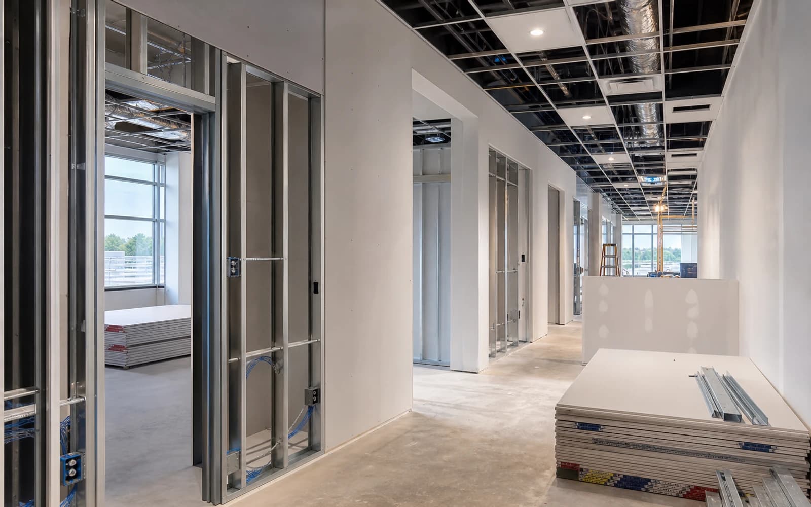 Commercial tenant improvement in progress with framing, ceiling grid, drywall, and organized materials
