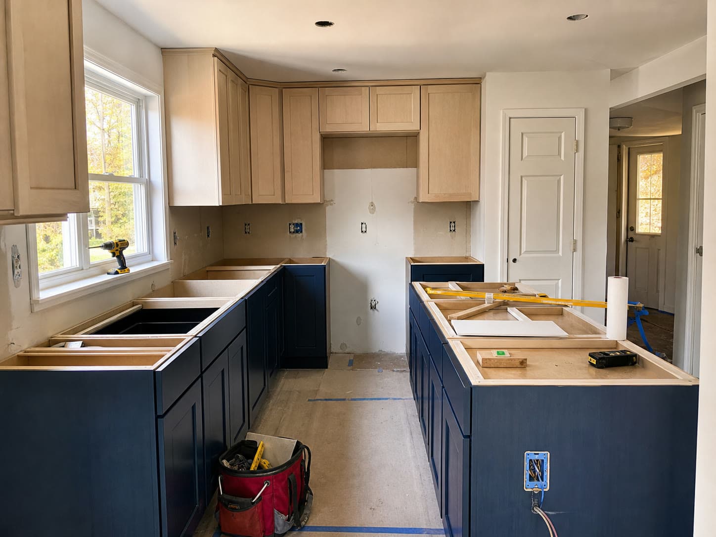 Residential kitchen remodel in progress with cabinets and protected work surfaces