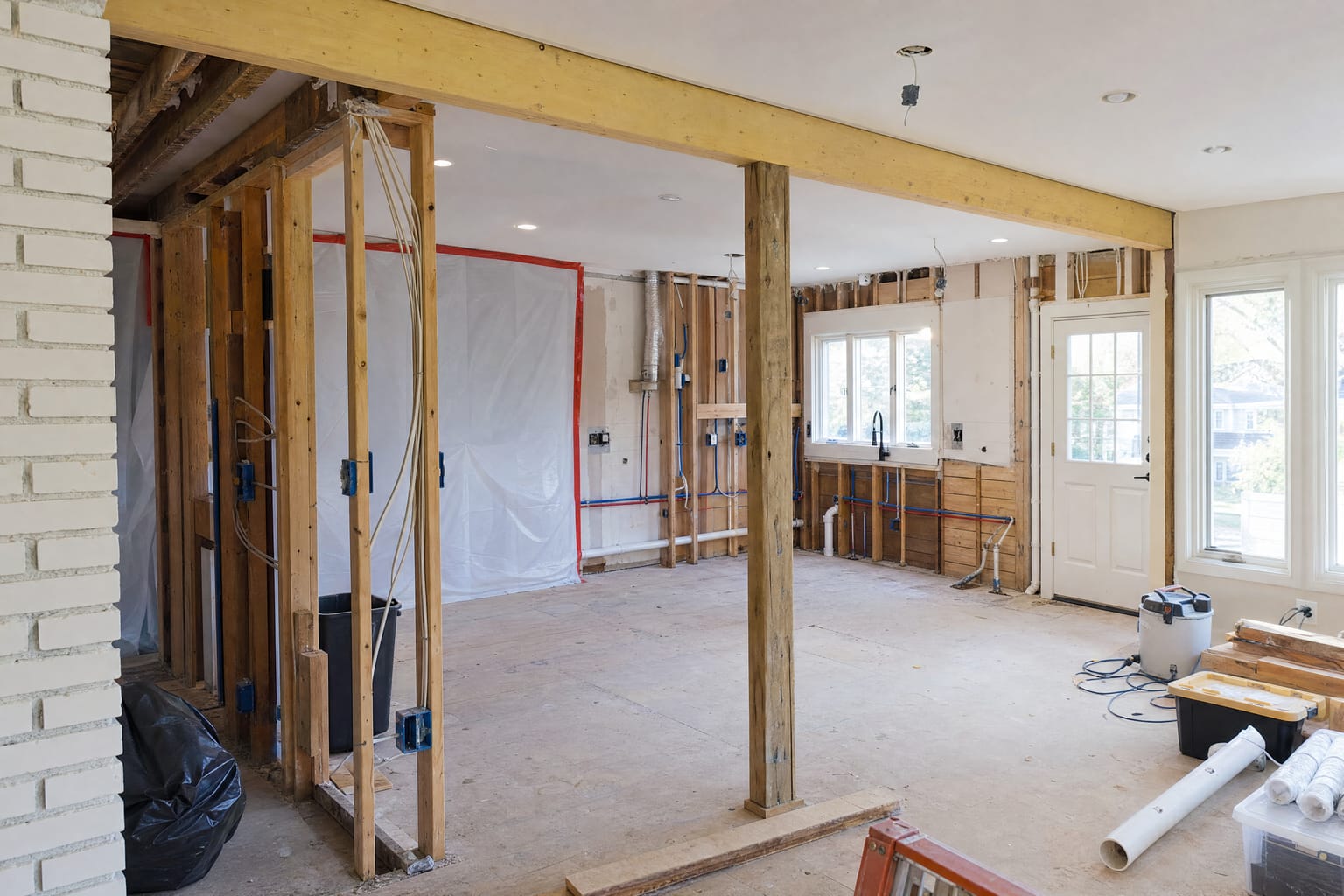 Kitchen gut renovation with temporary support beam, exposed framing, and rough electrical and plumbing